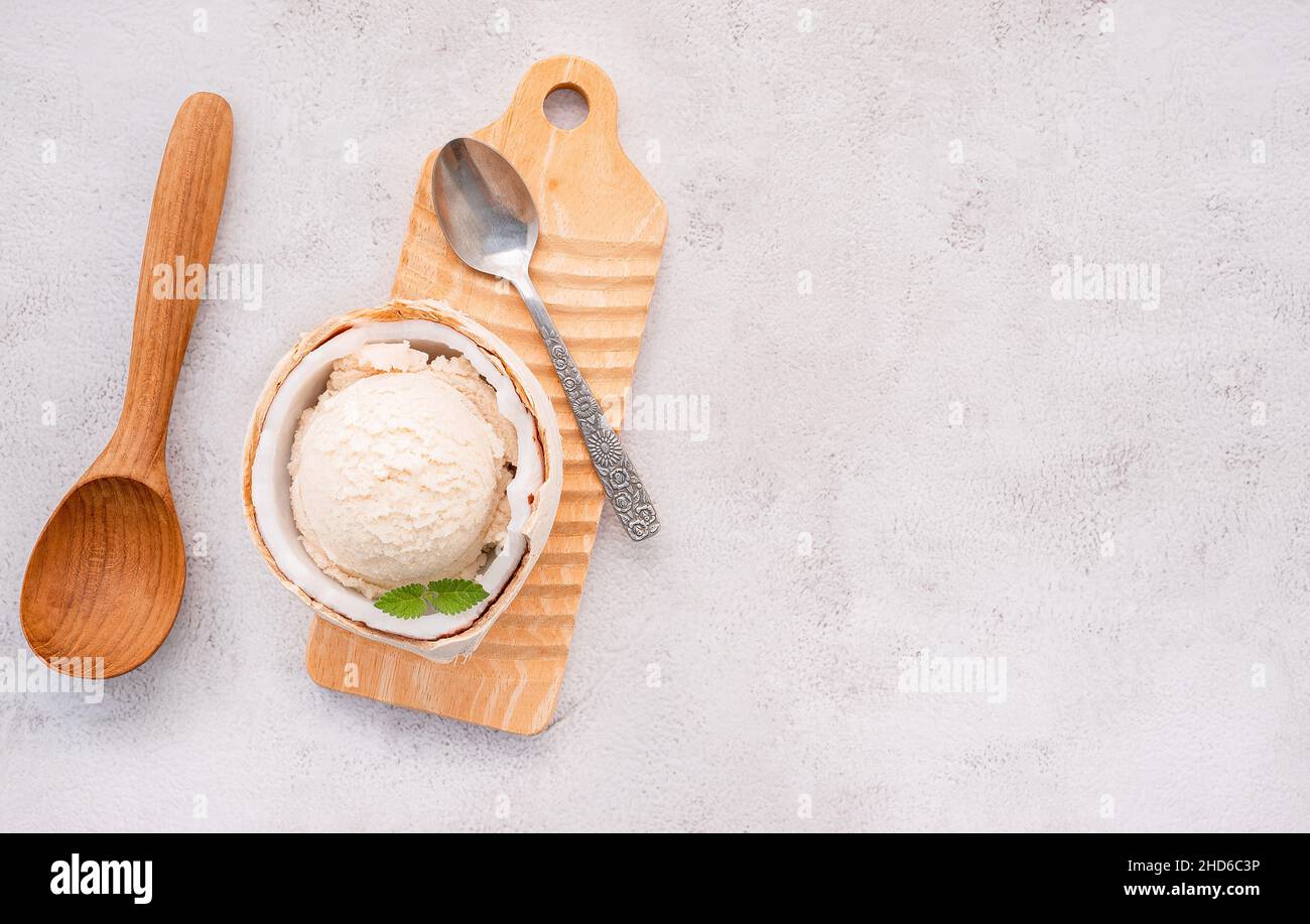 Kokoseis Aromen in der Hälfte der Kokosnuss Setup auf weißem Stein Hintergrund. Sommer und Süße Menükonzept. Stockfoto