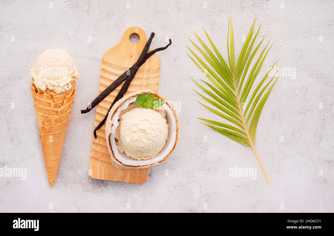 Kokoseis Aromen in der Hälfte der Kokosnuss Setup auf weißem Stein Hintergrund. Sommer und Süße Menükonzept. Stockfoto