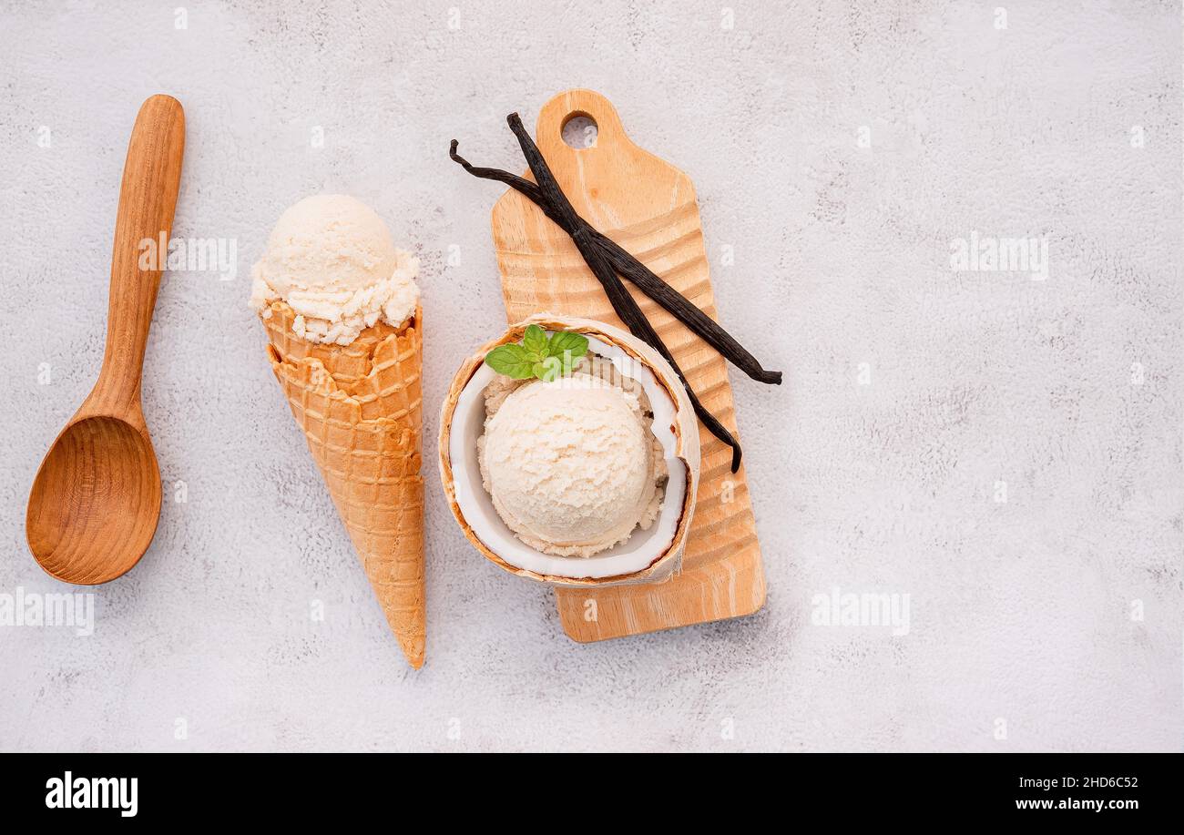 Kokoseis Aromen in der Hälfte der Kokosnuss Setup auf weißem Stein Hintergrund. Sommer und Süße Menükonzept. Stockfoto