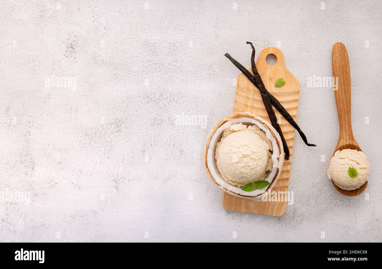 Kokoseis Aromen in der Hälfte der Kokosnuss Setup auf weißem Stein Hintergrund. Sommer und Süße Menükonzept. Stockfoto