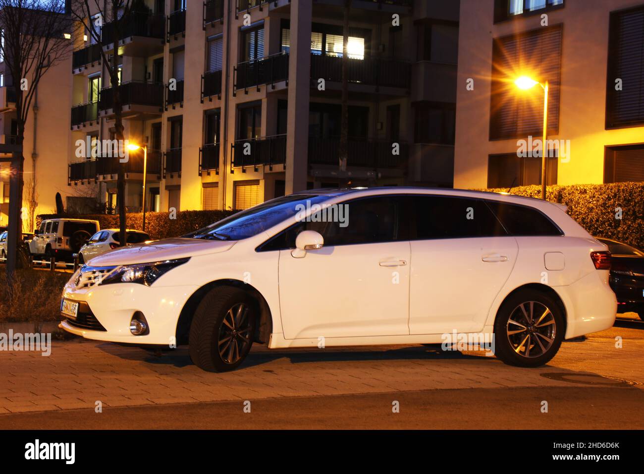 Weißer Toyota Avensis, aufgenommen im Dunkeln vor städtischem Hintergrund (Ludwigshafen, 16. Februar 2021) Stockfoto