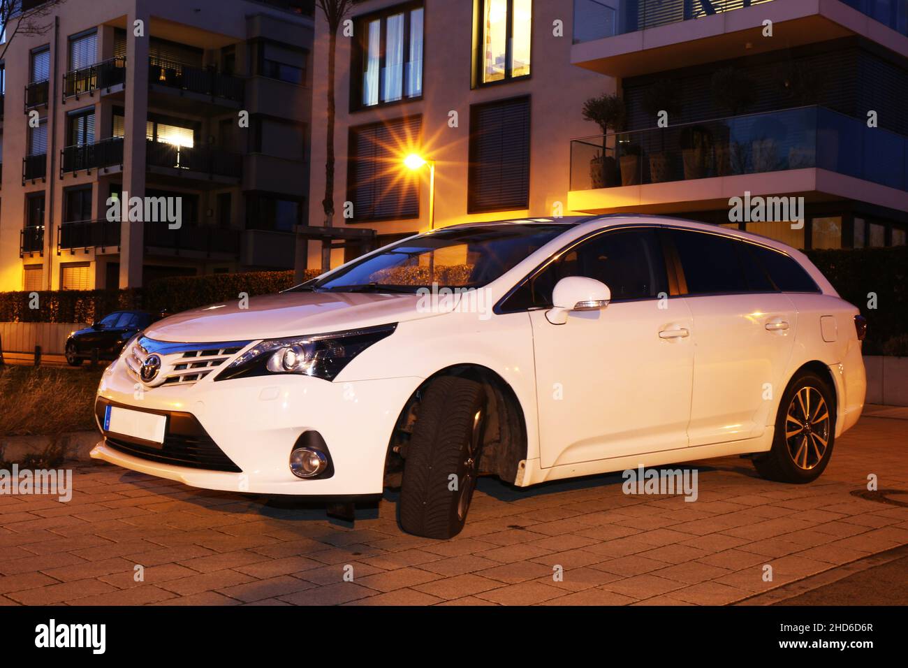 Weißer Toyota Avensis, aufgenommen im Dunkeln vor städtischem Hintergrund (Ludwigshafen, 16. Februar 2021) Stockfoto