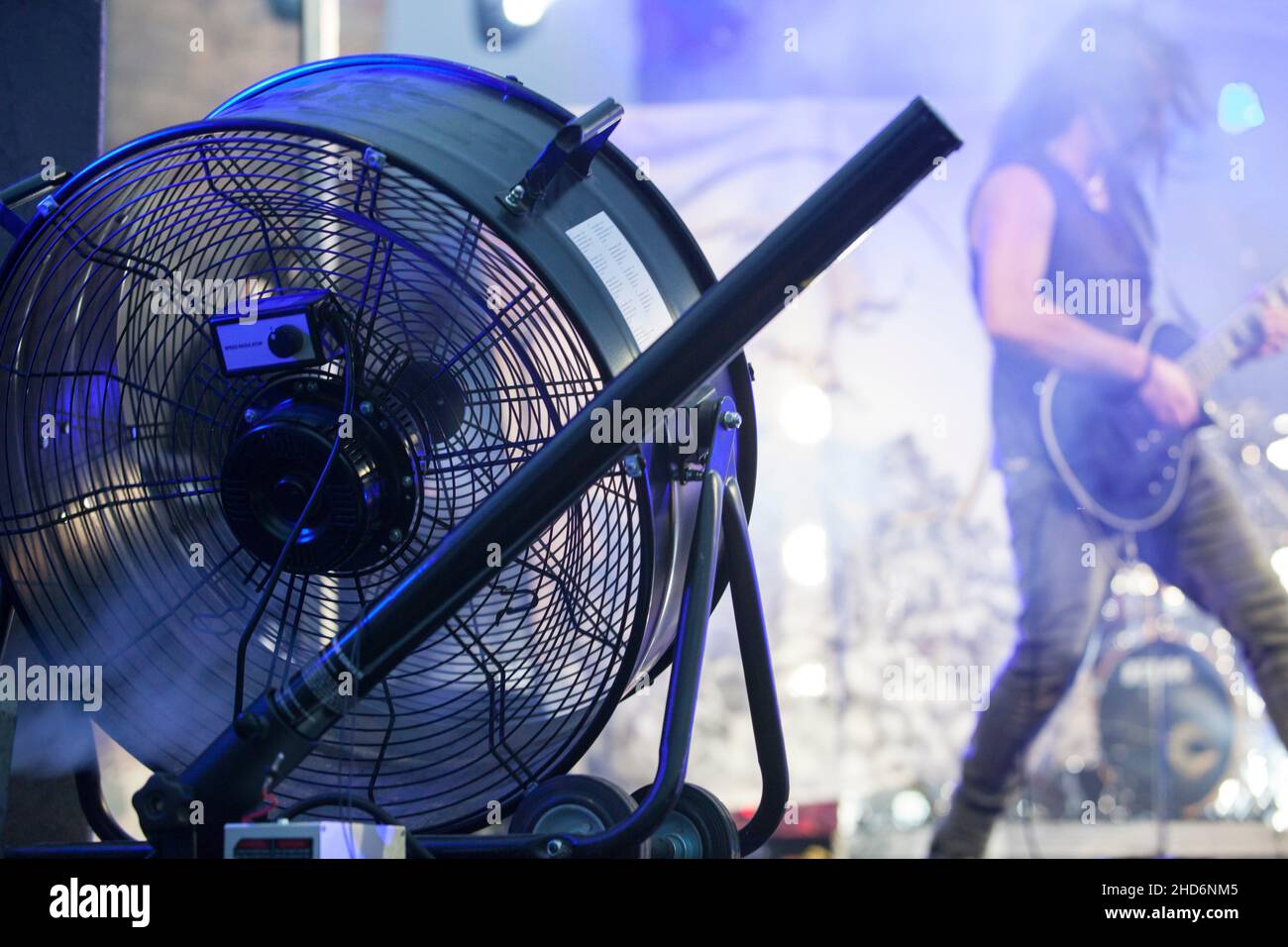 Bühnengebläse, die bei Live-Rock-Performance mit einer Dunstmaschine verwendet wird. Musiker im Hintergrund. Stockfoto
