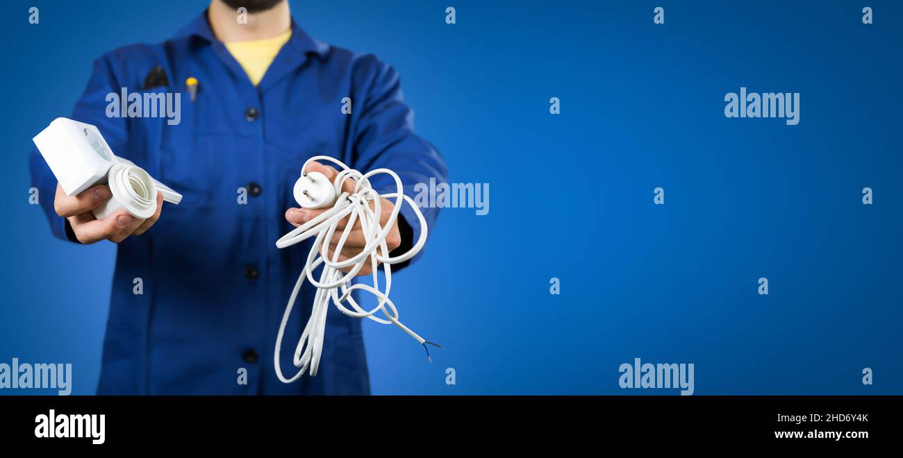 Elektriker mit elektrischer Versorgung in Händen auf blauem Hintergrund. Banner-Kopierraum Stockfoto