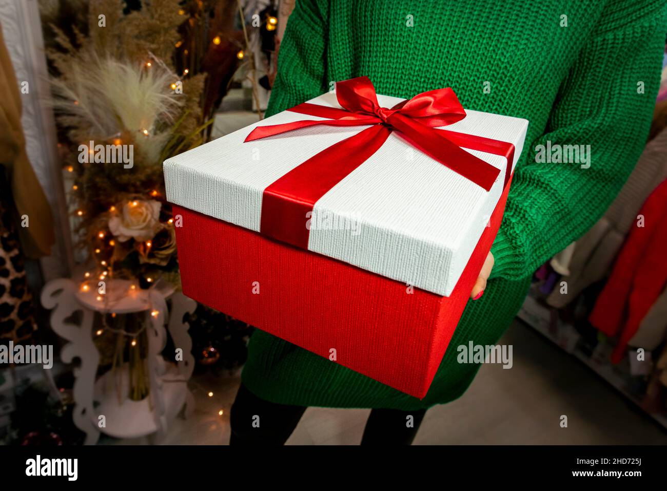 Frau im grünen Pullover hält präsent. Weihnachten, Neujahr, Geburtstag, Valentinstag Konzept. Stockfoto