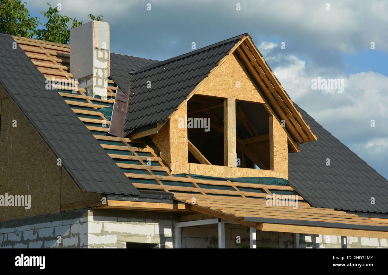 Ein Haus im Bau mit einer Nahaufnahme der Dachkonstruktion auf der Bühne des Dachs über einer Dampfsperre, Metallfliesen und Blinkeinbauten Stockfoto