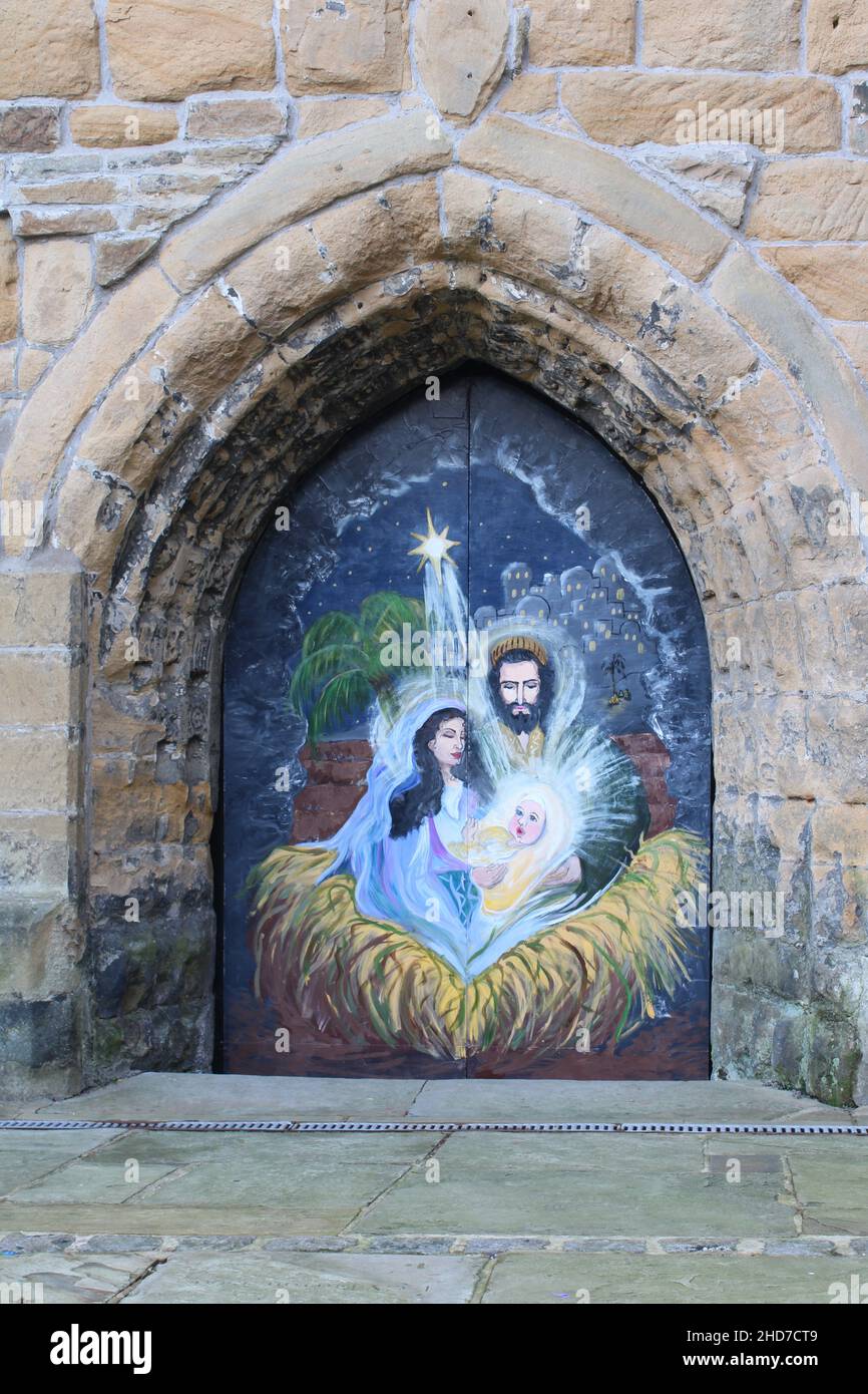 Wandbild von Maria Joseph und dem Jesuskind an den Kirchentüren mit Mauerwerk-Torbogen in der St. Thomas the Martyr Church, Upholland, Lancashire, Großbritannien, Stockfoto