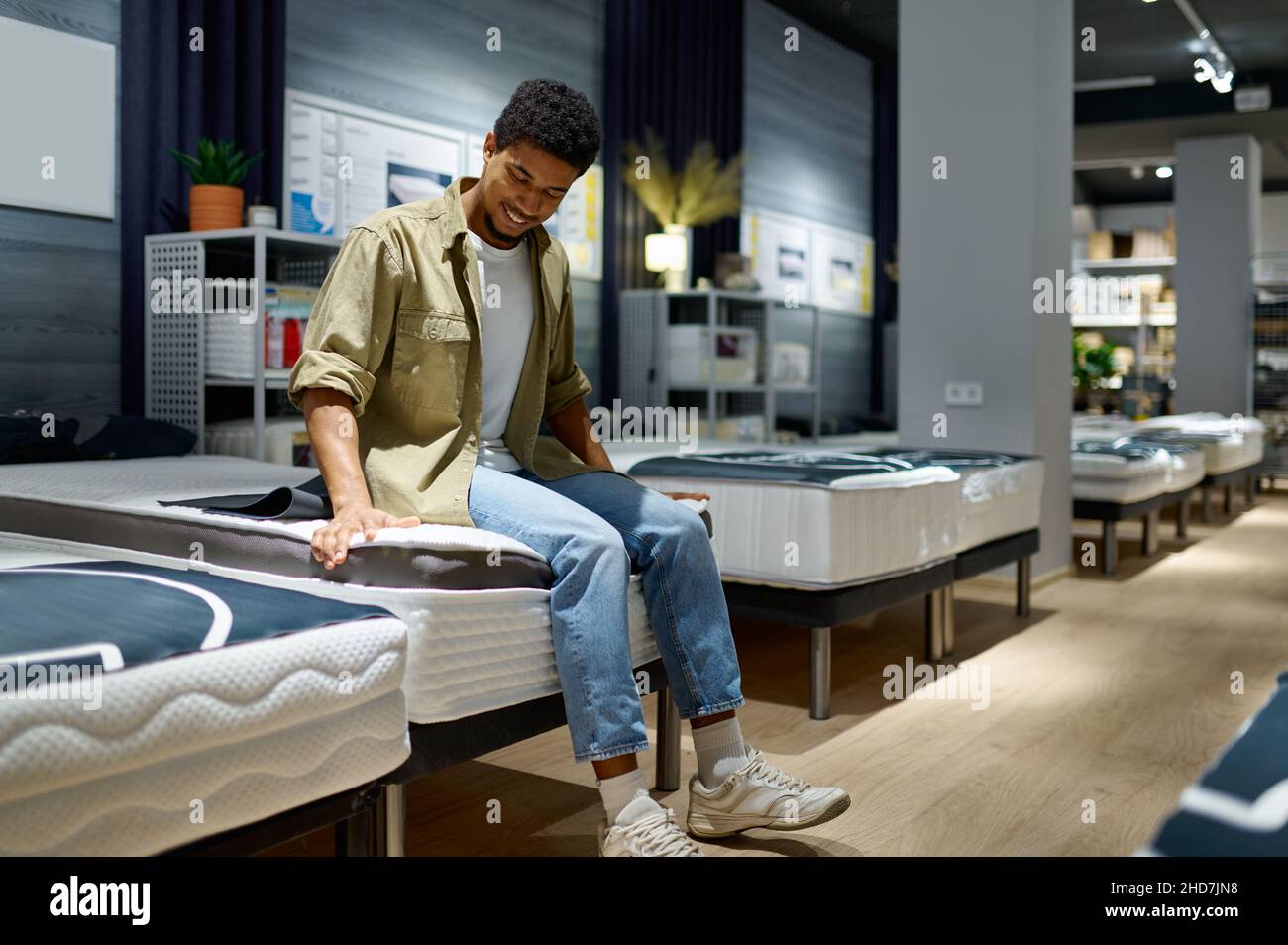 Mann, der sich für eine Matratze entscheidet, sitzt auf einem Lader Stockfoto