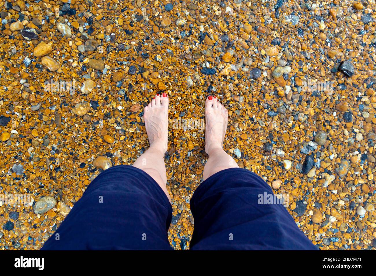 Füße tauchen im Meer an einem Kiesstrand in Saltdean, Großbritannien Stockfoto