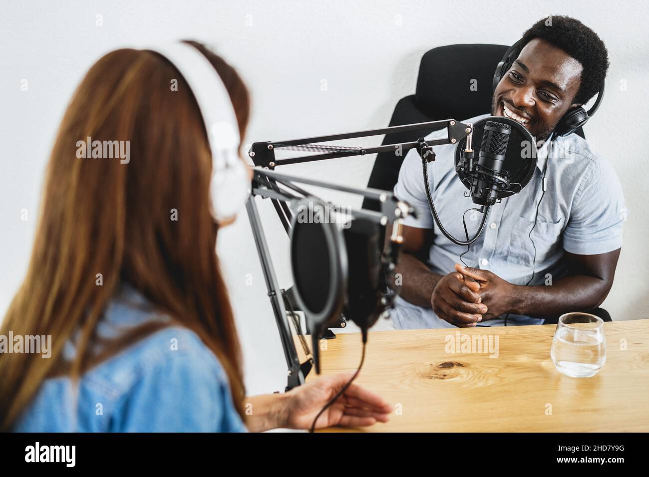 Gastgeber, die gemeinsam Podcast-Sessions abhalten - Afrikanischer Sprecher, der während des Live-Streams ein Interview macht - Schwerpunkt auf Mikrofon Stockfoto