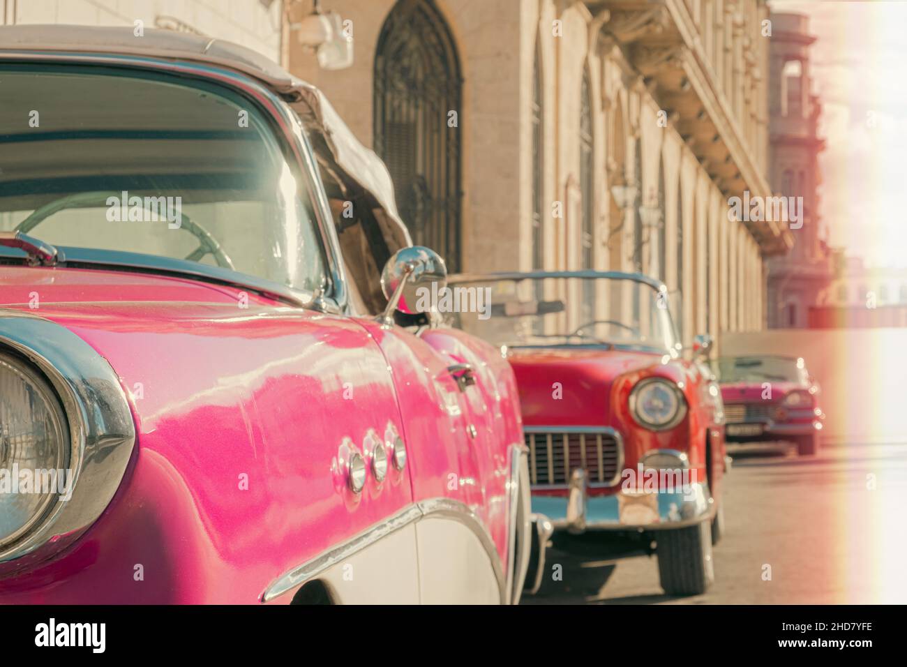 Oldtimer-Autos parken in Reihe mit historischem Gebäudehintergrund in Havanna. Cineamatic-Look mit leichtem Leck. Stockfoto