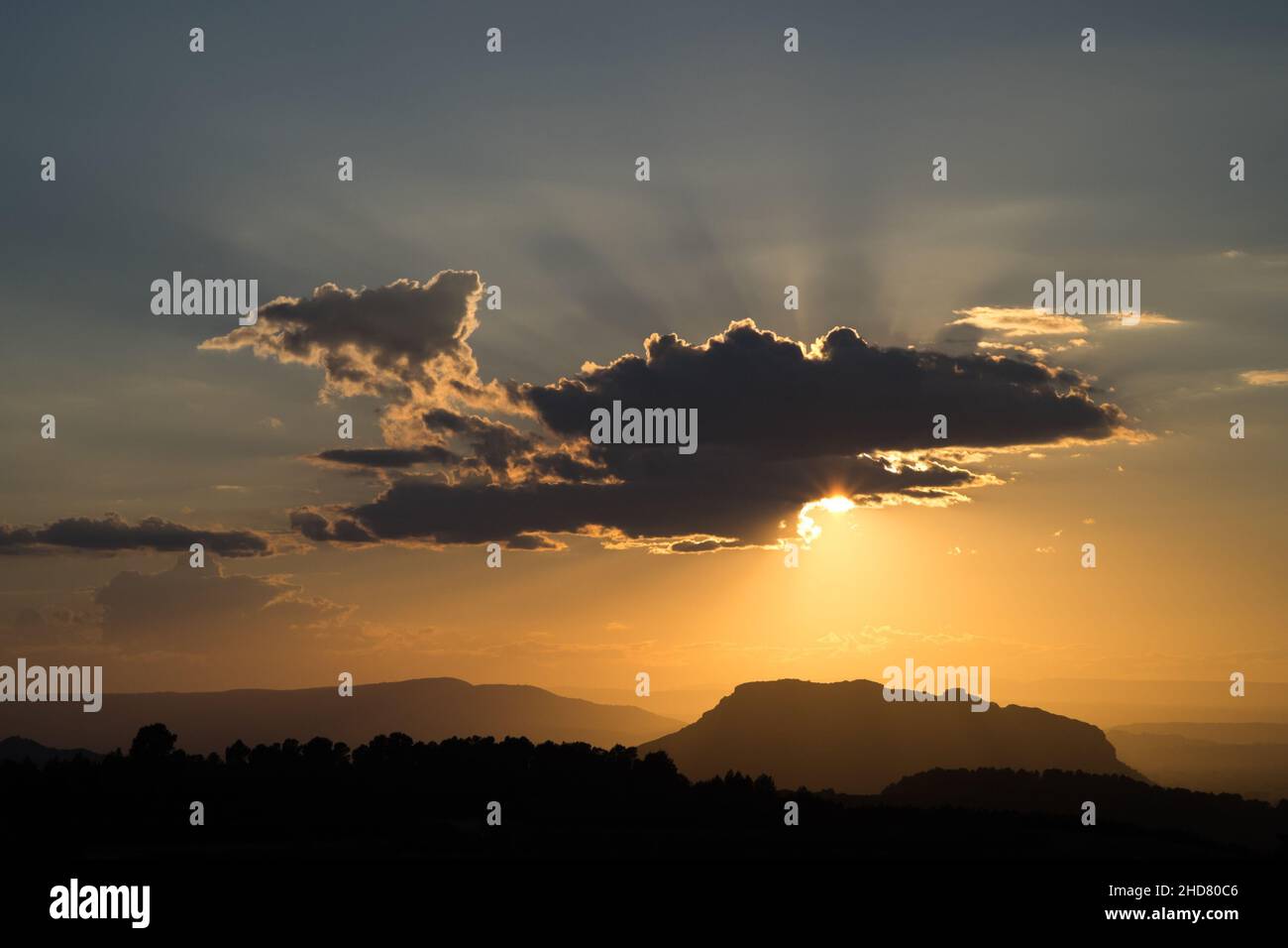 Herrliches Licht und herrliche Sonnenstrahlen, während die Sonne kurz vor Sonnenuntergang aus einer Wolke über den Hügeln von spanien valenciana guckt Stockfoto