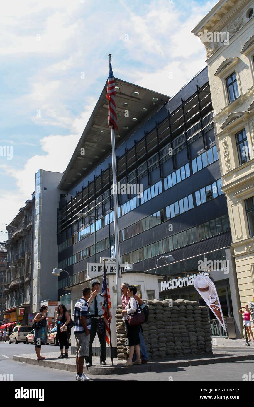 Menschenmenge am Wachposten der US-Armee am Checkpoint Charlie. Ehemaliger Grenzübergang zwischen West- und Ost-Berlin kalter Krieg. Wolken blauer Himmel Hintergrund. Stockfoto