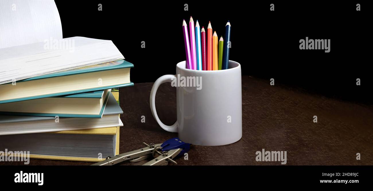 Konzept der Bildung und Vorbereitung auf die Schule. Stapel von bunten Büchern, Bleistifte auf schwarzem Hintergrund, Beginn des Schuljahres Stockfoto