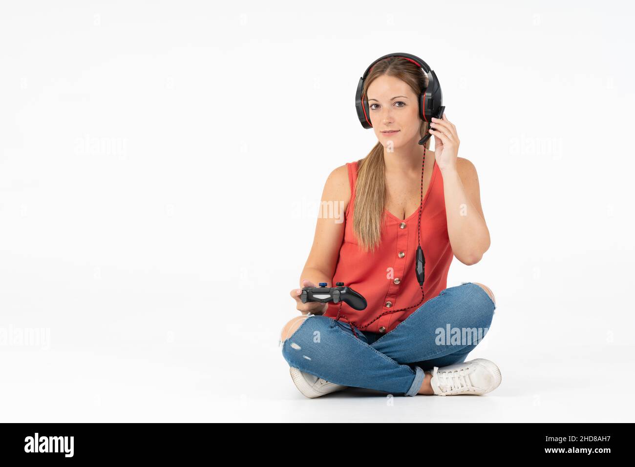 Frau spielt Videospiele mit einem Controller und Kopfhörern auf weißem Hintergrund Stockfoto