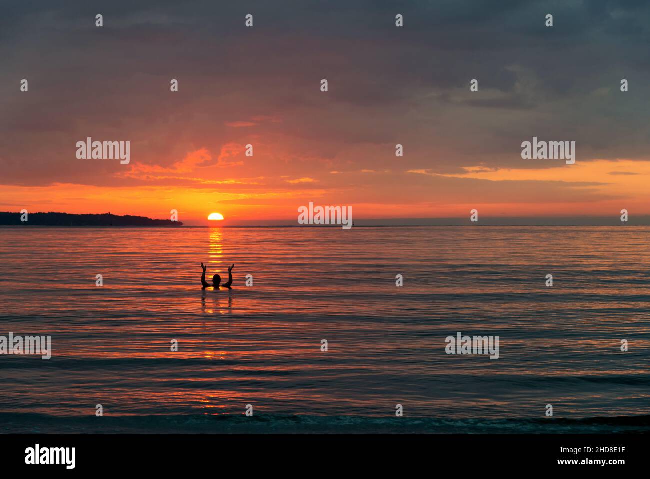 Schöner feuriger Sonnenaufgang am Strand und eine menschliche Silhouette, die die aufgehende Sonne in seinen Händen hält - Platz für Text Stockfoto