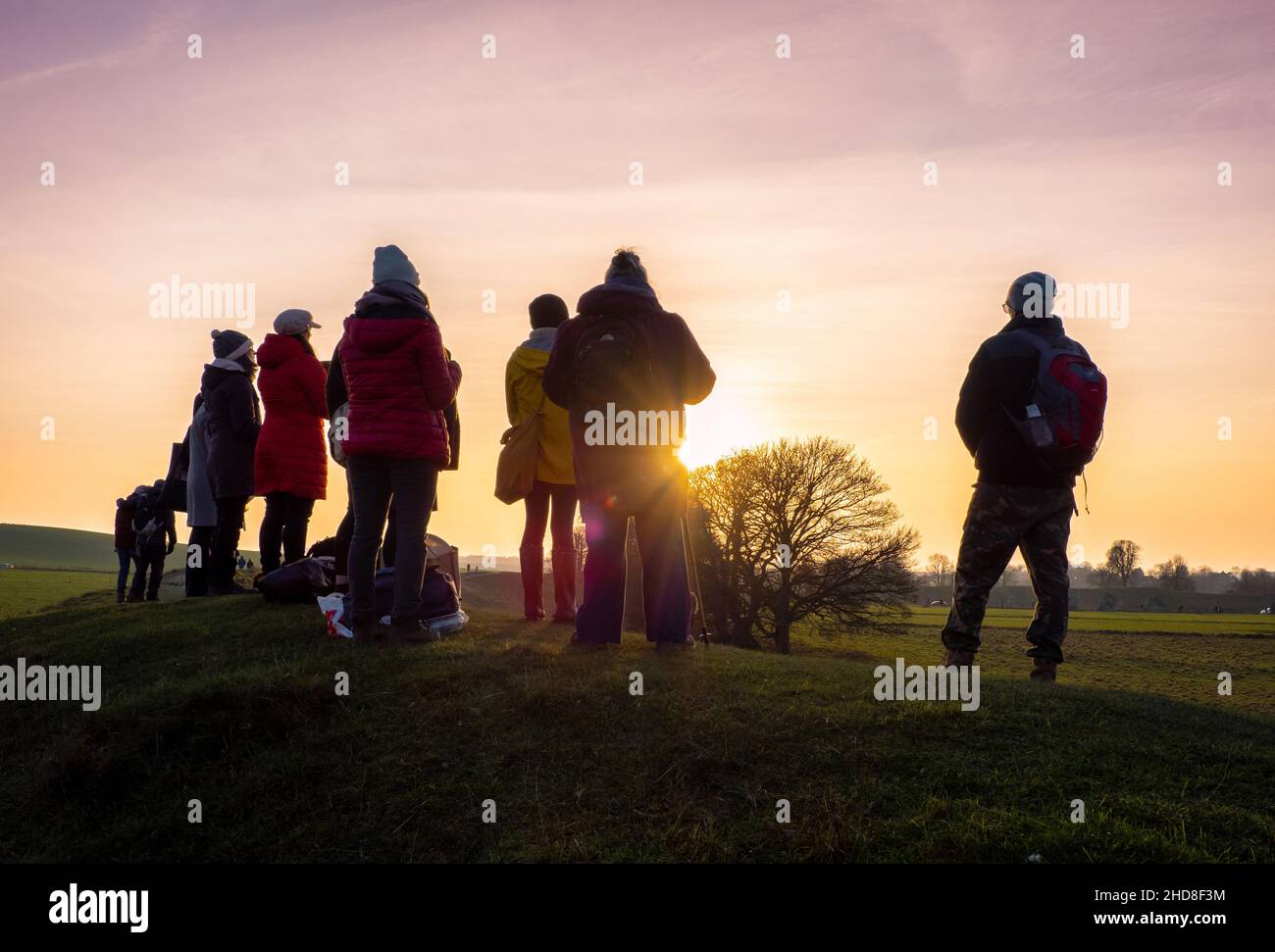 Eine Band von Sängern, die die untergehende Sonne mit mystischer Musik bei der Wintersonnenwende 2021 in Avebury in Wiltshire, Großbritannien, behulten Stockfoto