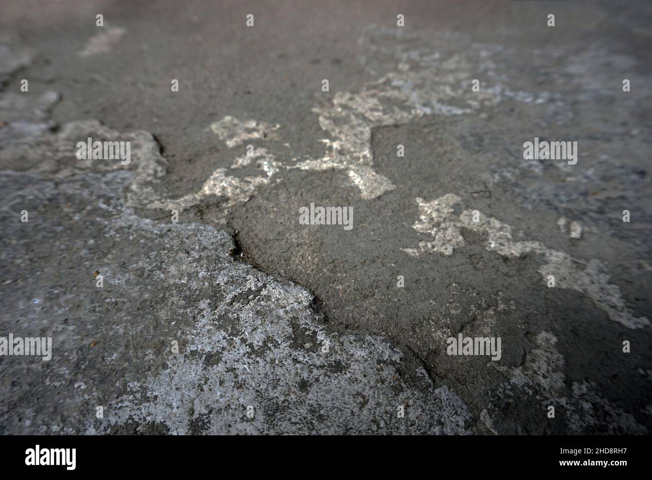 Rissiger Zement, der mit einer grauen Zementoberfläche als Hintergrund für die Konstruktion bedeckt ist Stockfoto