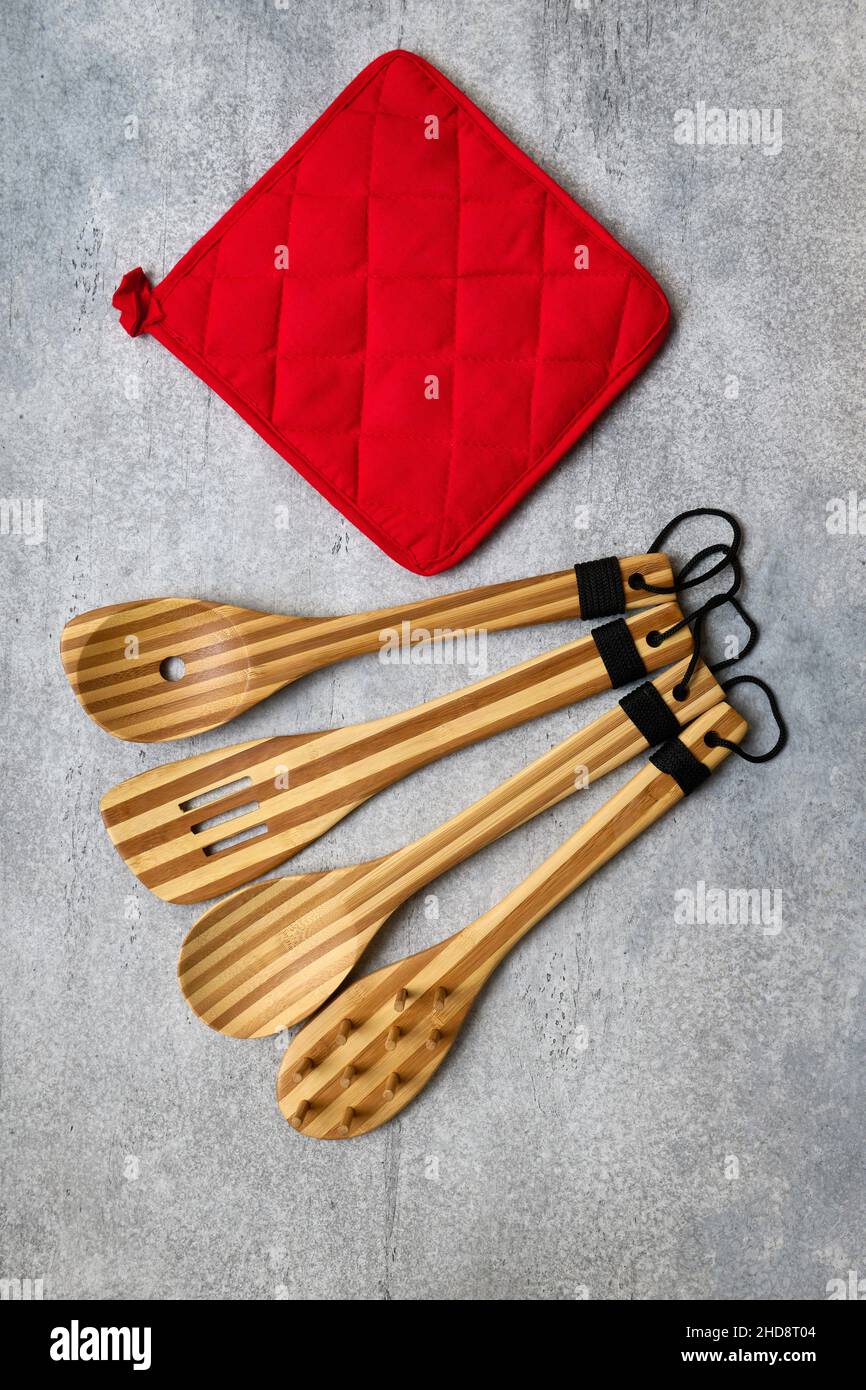 Küchengeräte aus Bambus aus Holz und roter Ofenhandschuh auf grauem Betongrund Stockfoto