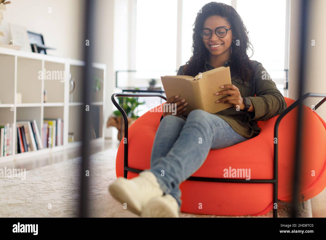 Lächelnde schwarze Frau in Brille, die Buch liest Stockfoto