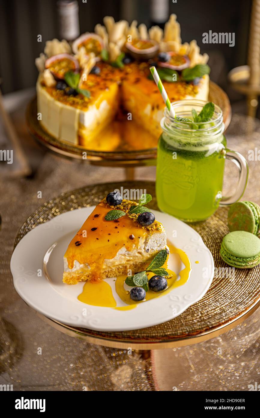 Passionsfrucht-Käsekuchen. Dessert mit tropischem Geschmack auf einem weißen Teller serviert mit Minzlimonade Stockfoto