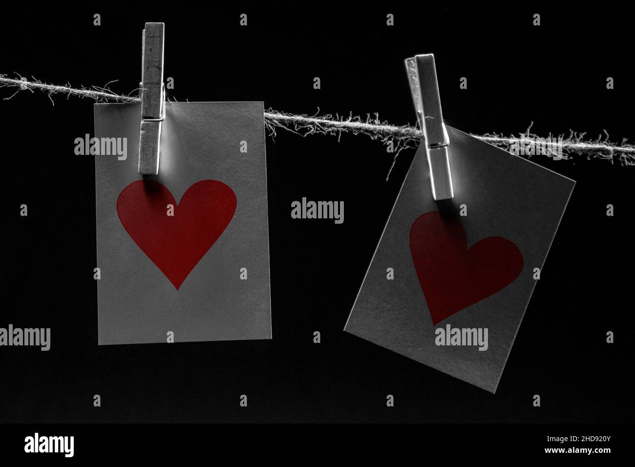 Eine Jute Wäscheleine, zwei Klamotten (Clips), zwei rote Herzen auf zwei mit Notizkarten, um eine Botschaft für Liebe, valentinstag und Leidenschaft, Herzband zu vermitteln Stockfoto