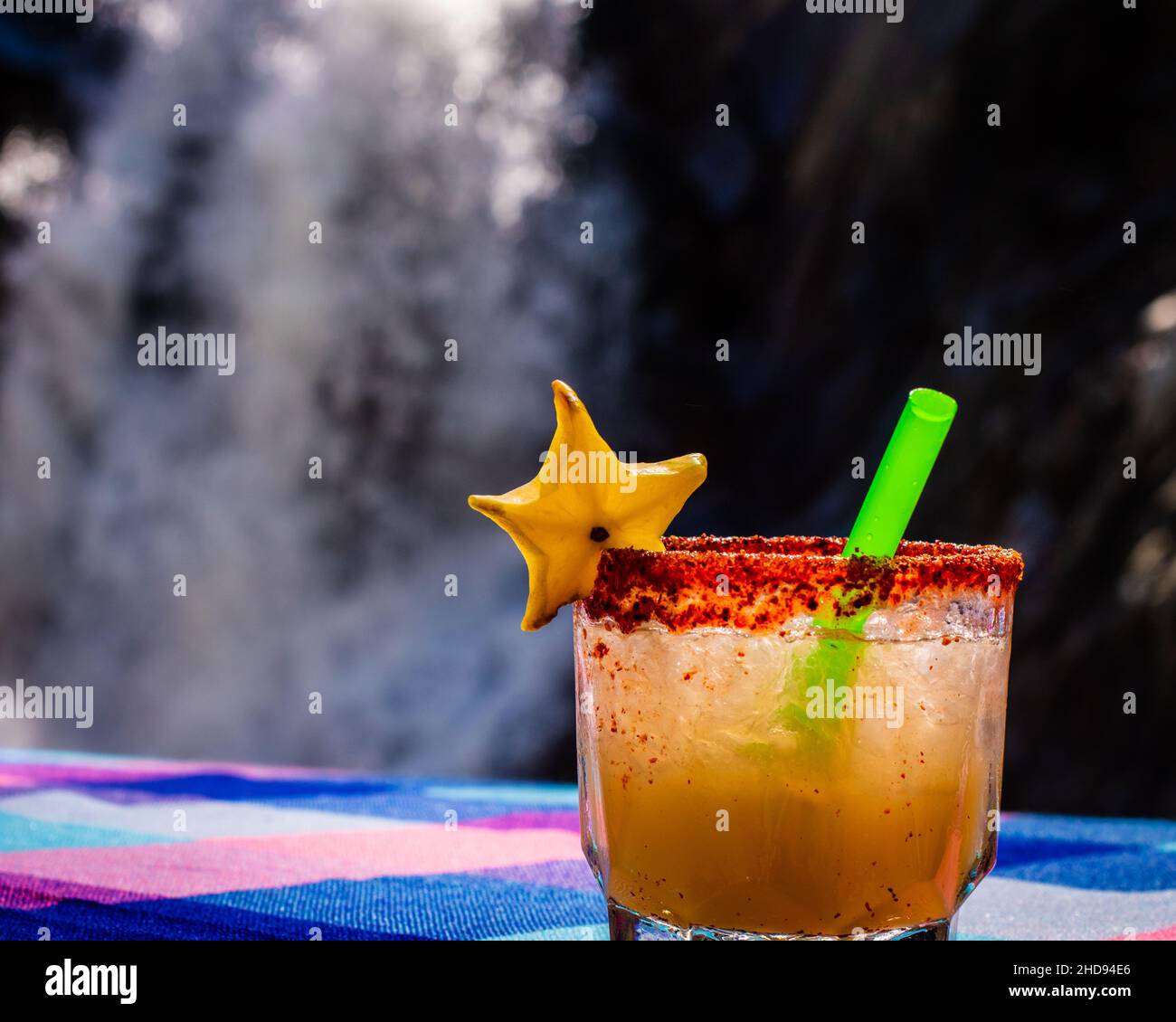 Nahaufnahme eines Mai Tai Cocktails auf einem Tisch vor einem Wasserfall Stockfoto