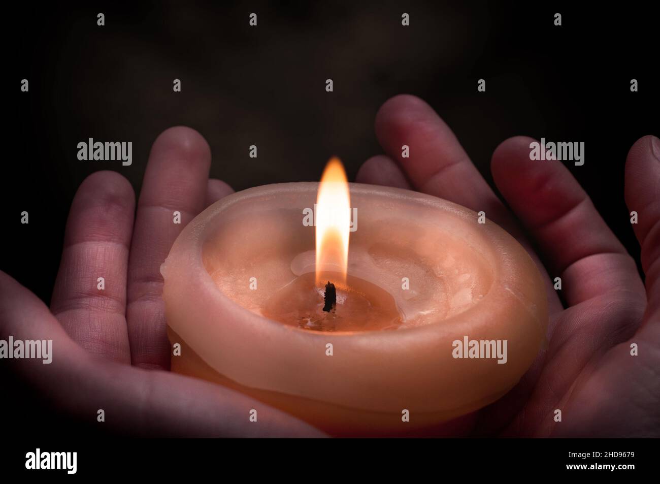 Eine brennende Kerze in der Hand in der Dunkelheit Stockfoto