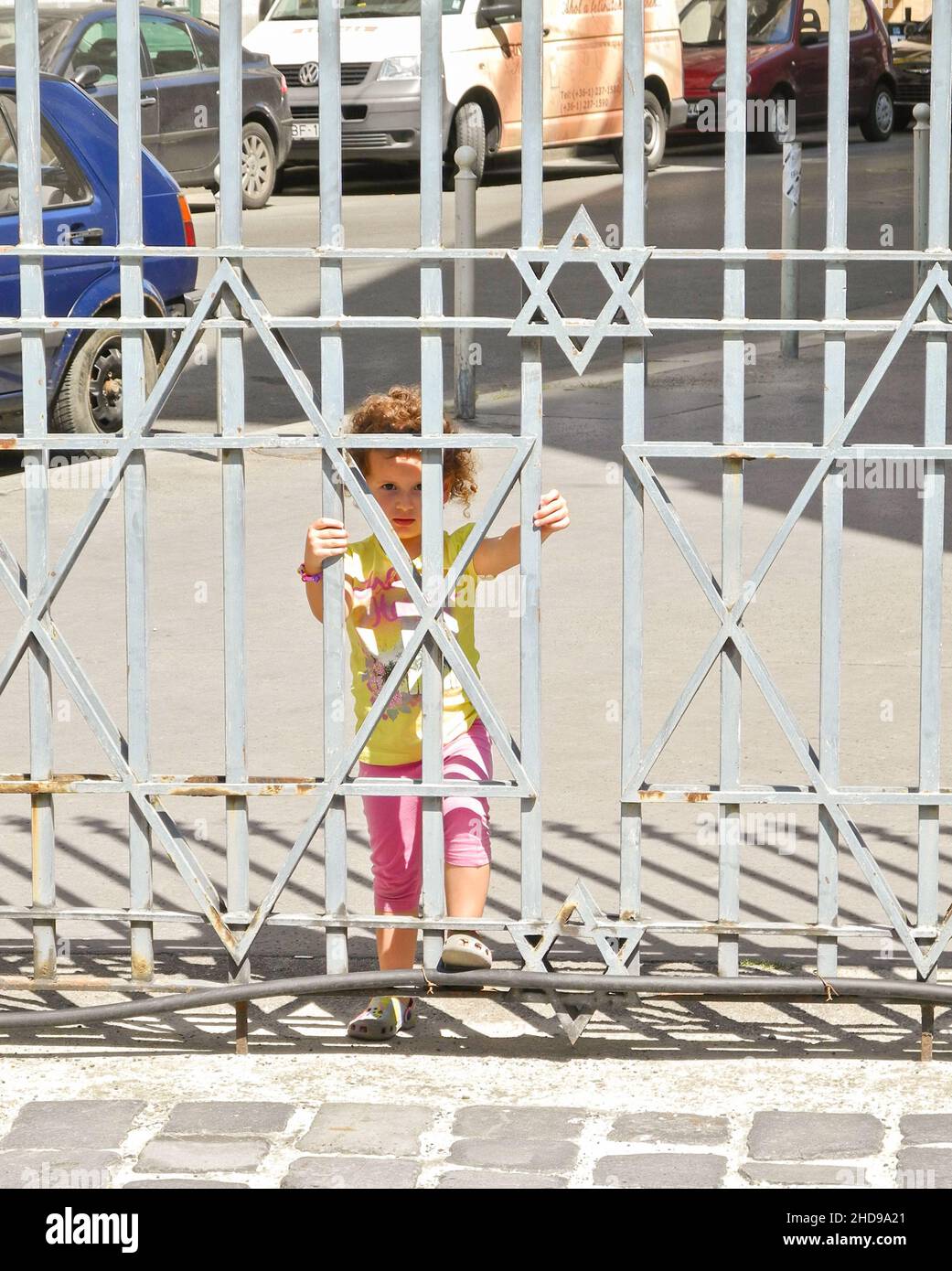 Ein junges Mädchen, das die rostigen Tore der Synagoge in der Dohány-Straße hält, auch bekannt als Tabakgasse-Synagoge, Erzsébetváros, Budapest, Ungarn, Europa. Stockfoto