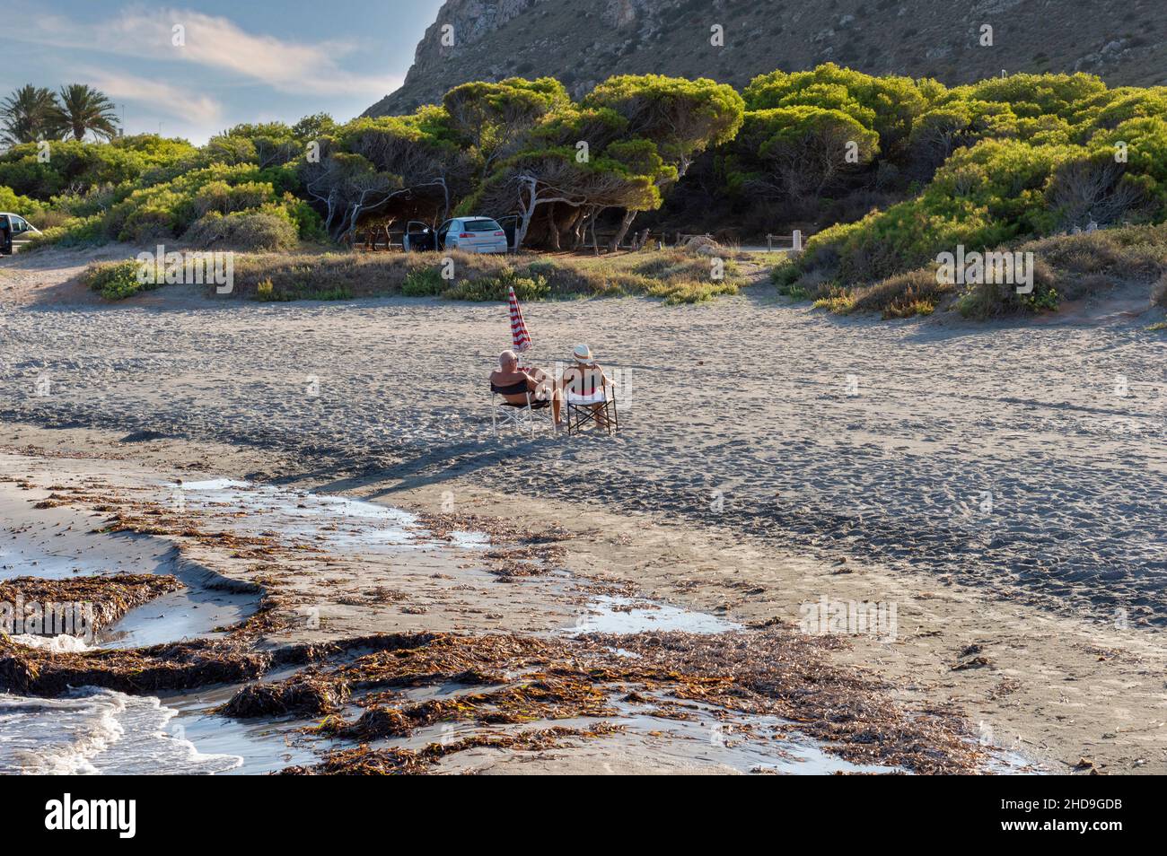 Das ältere Paar genießt die Zeit am Strand an einem sonnigen Nachmittag, sitzt hinter dem Meer, in einer Bucht in Santa Pola, Alicante, Sapin Stockfoto
