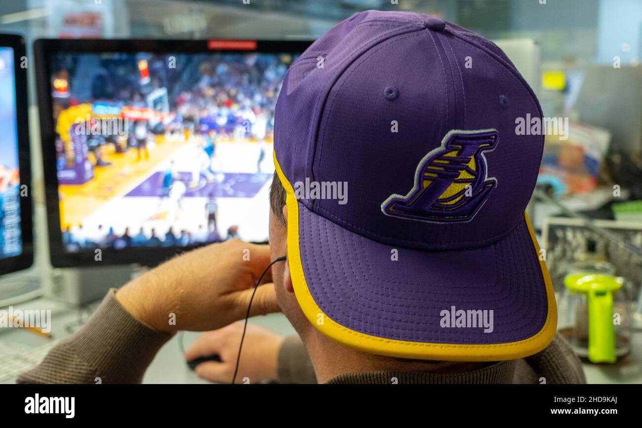 9. September 2021, Los Angeles, Kalifornien. Ein Fan, der eine Baseballmütze mit dem Logo der Los Angeles Lakes trägt, sieht Basketball auf einem Computermonitor. Stockfoto