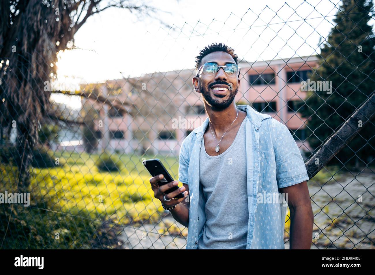 Porträt eines gutaussehenden lateinamerikanischen Mannes, der sein Smartphone auf der Straße lächelt Stockfoto