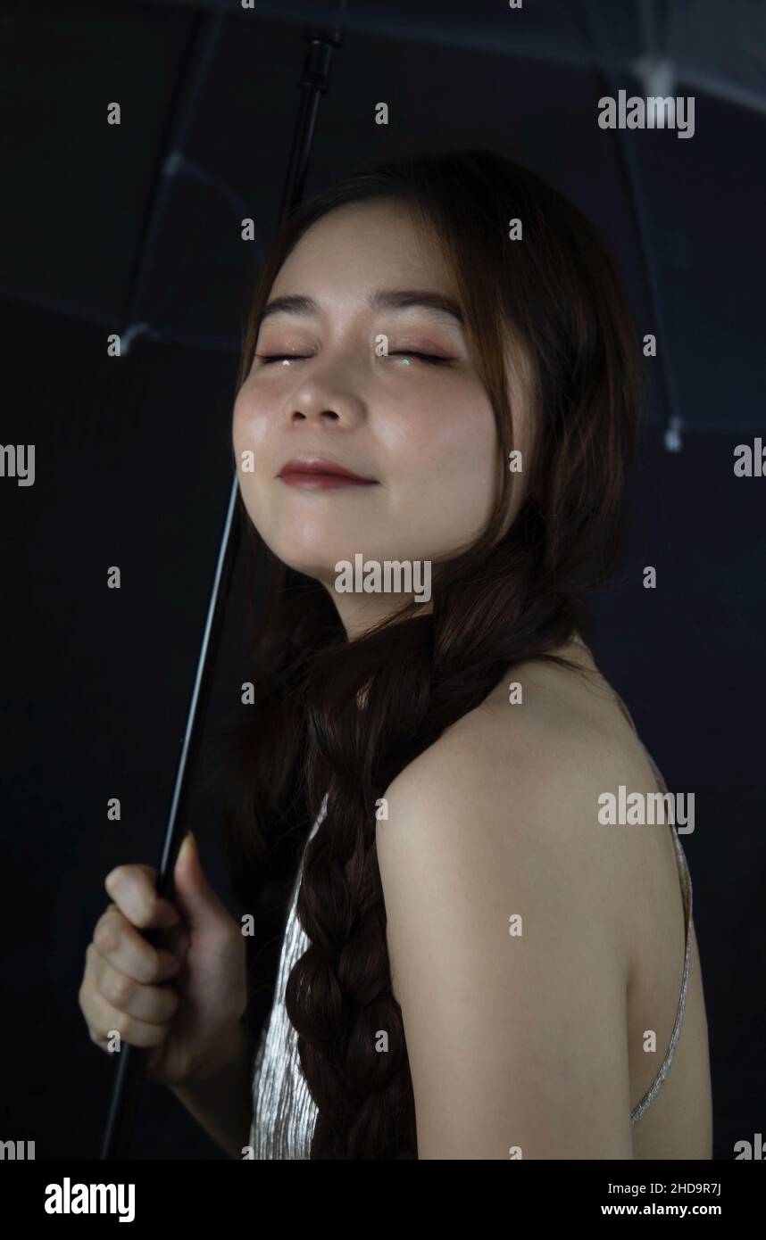 Porträt einer lächelnden schönen jungen Frau aus Vietnam mit einem Regenschirm Stockfoto