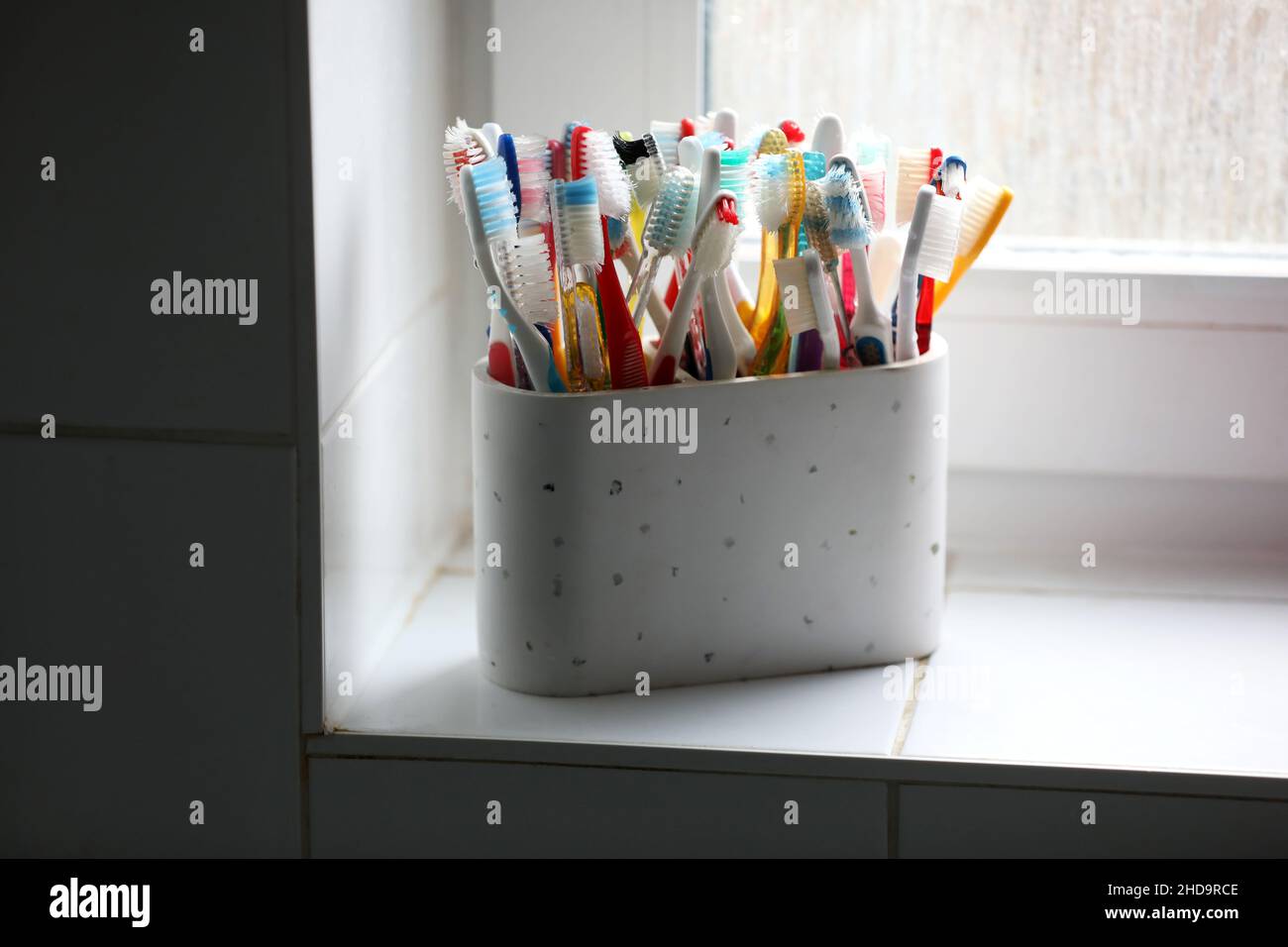 Eine Auswahl an bunten Zahnbürsten aus Kunststoff in einem Topf in einem Badezimmer in Chichester, West Sussex, Großbritannien. Stockfoto