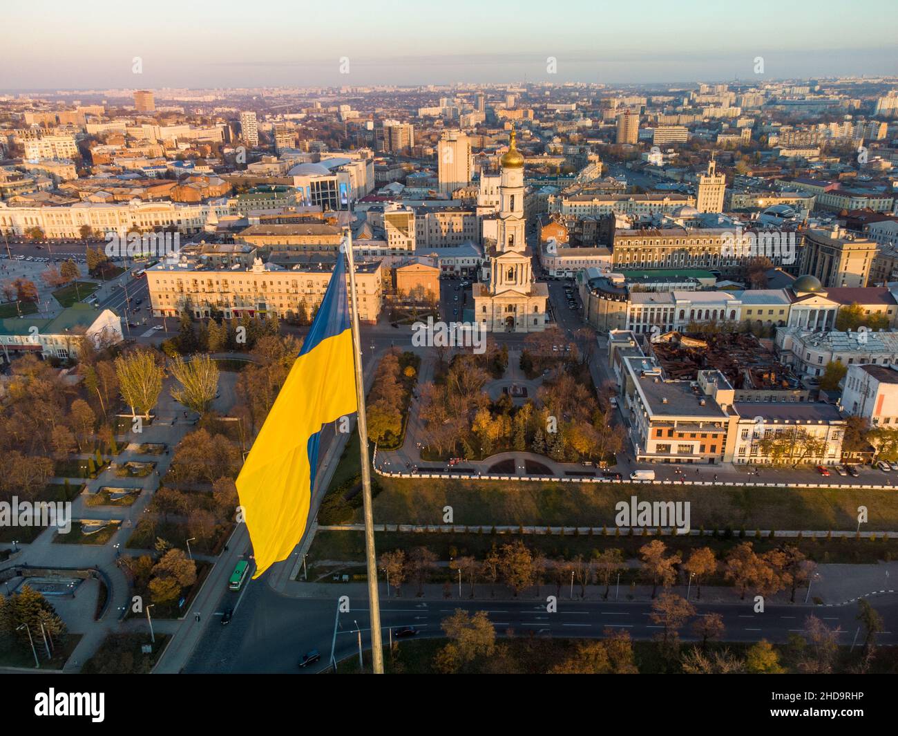 Flagge der Ukraine mit herbstlichem epischem Sonnenuntergang, sonniger Stadtansicht. Stadtansicht mit der Dormition-Kathedrale und klarem Himmel in Kharkiv, Ukraine Stockfoto