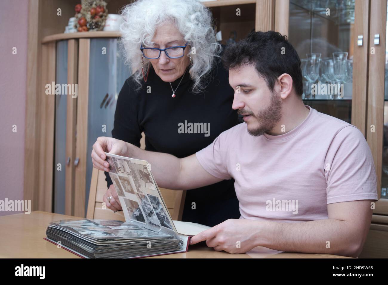 Reife Mutter und erwachsener Sohn sehen alte Schwarz-Weiß-Fotos im Album aus. Stockfoto