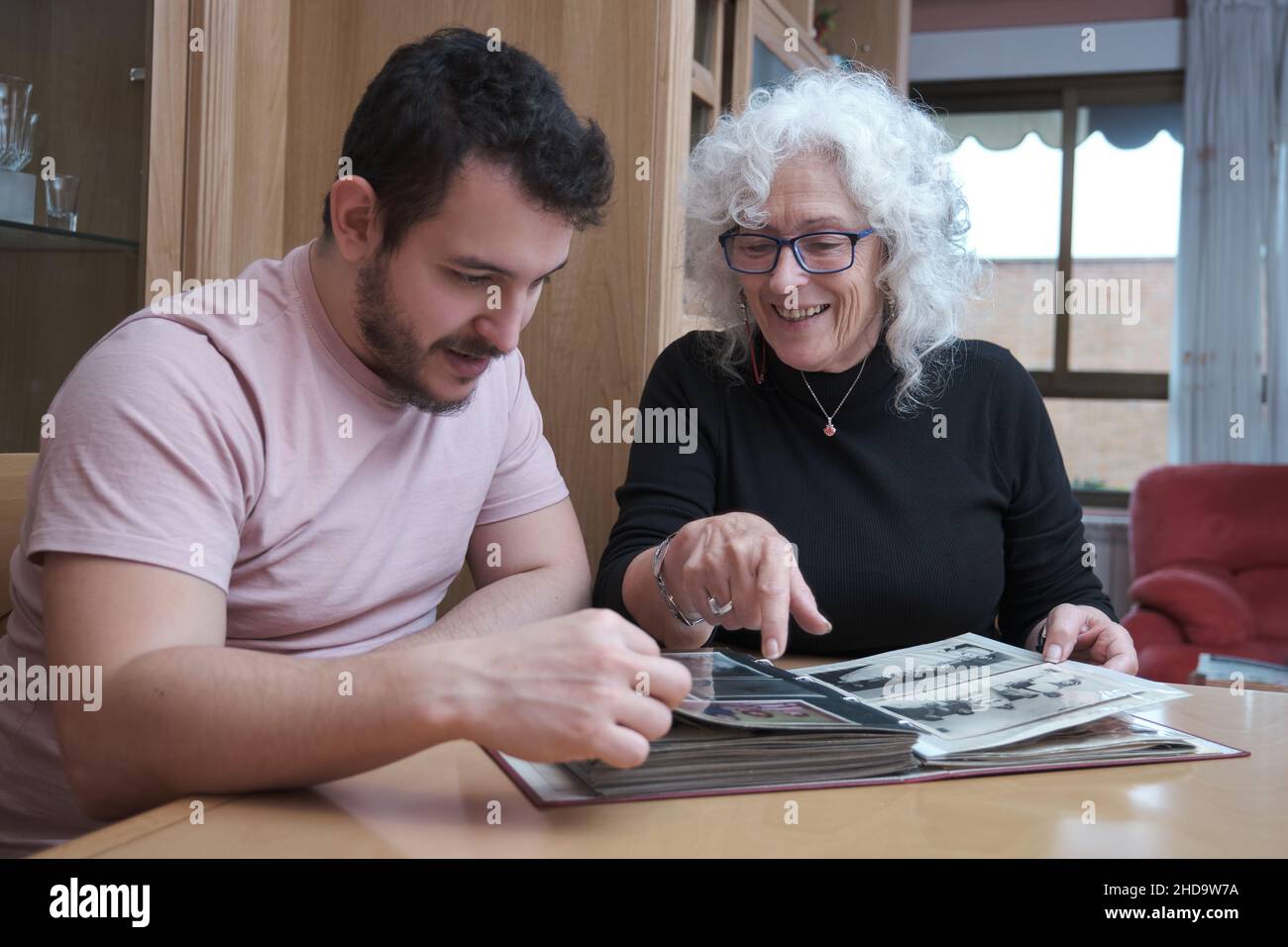 Reife Mutter und erwachsener Sohn verbringen Zeit miteinander und schauen sich altes Album an. Stockfoto