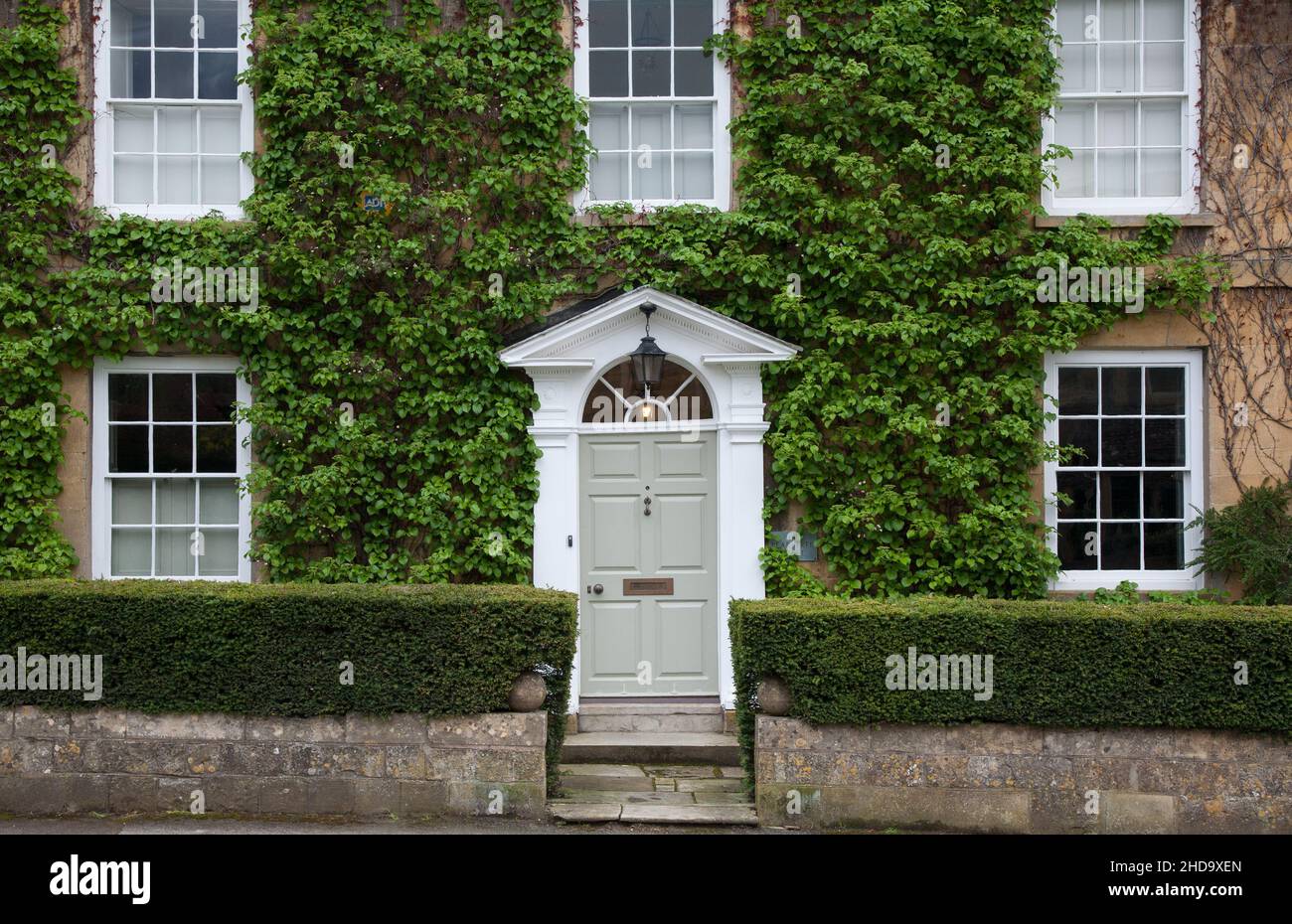 Vordereingang des traditionellen Efeu bedeckten Cotswold Steinhauses im Broadway House Stockfoto