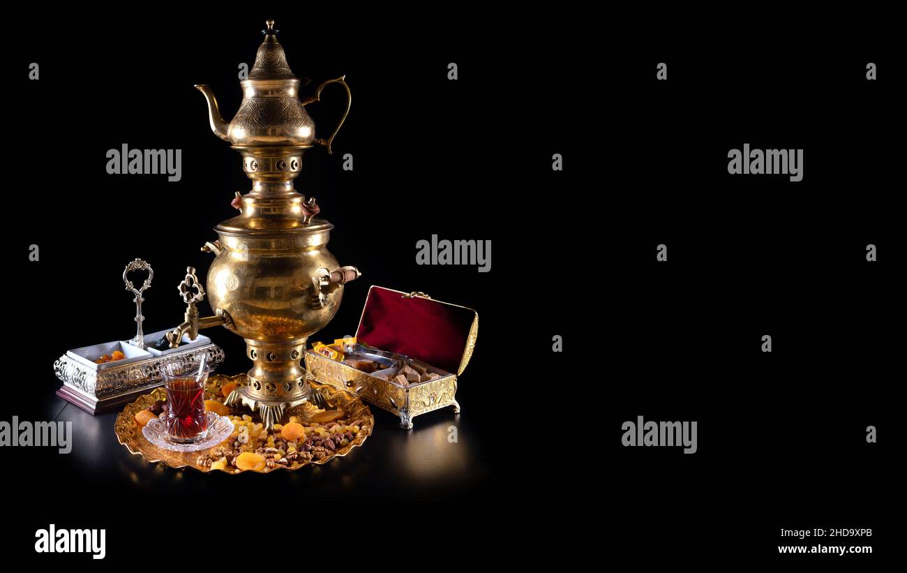 Orientalischer Tee in einem Samowar, mit Süßigkeiten auf schwarzem Hintergrund Stockfoto