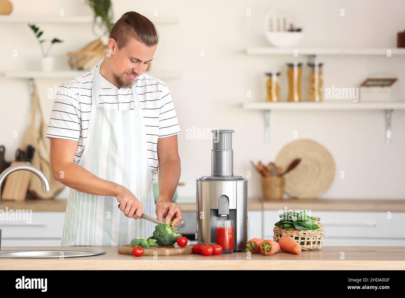 Junger Mann, der in der Küche gesunden Gemüsesaft zubereitet Stockfoto