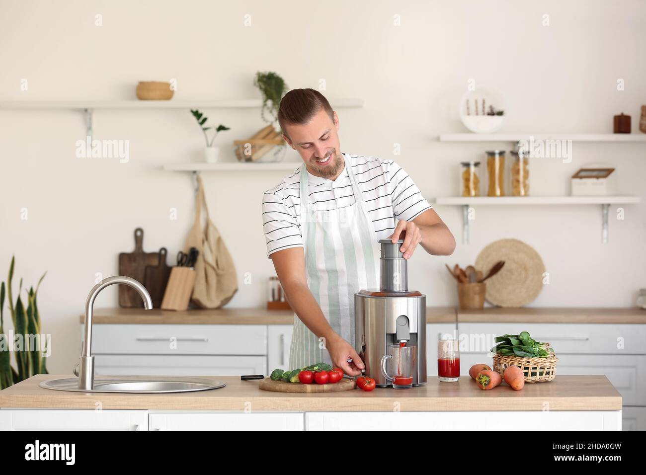 Junger Mann, der in der Küche gesunden Gemüsesaft zubereitet Stockfoto