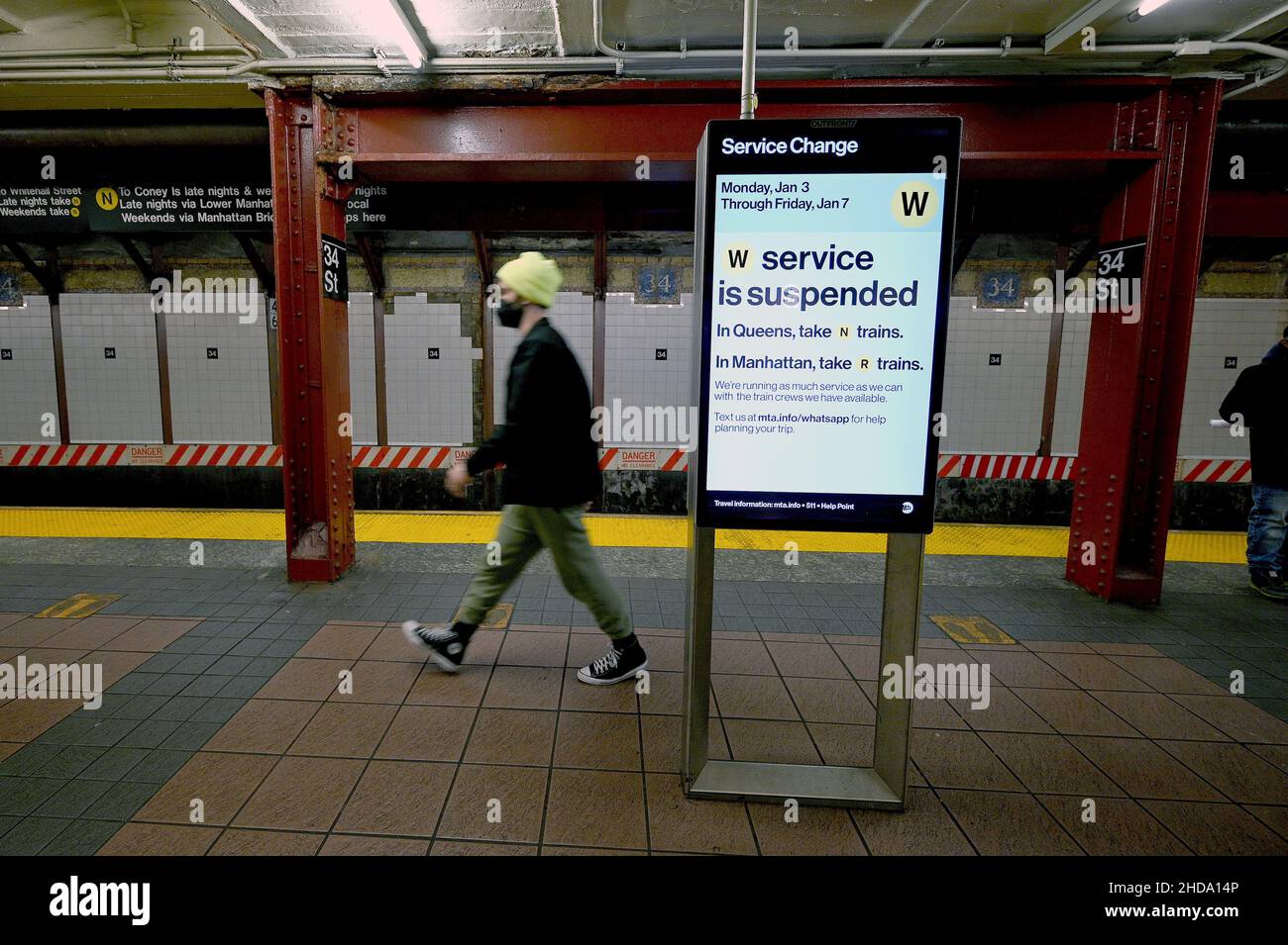 New York, USA. 04th Januar 2022. Ein Mann geht entlang der U-Bahn-Plattform N, R, W an einem elektronischen Schild vorbei, auf dem bekannt gegeben wird, dass die MTA (Metropolitan Transportation Authority) die W-Linie wegen eines Mangels an Besatzung aufgrund des Anstiegs der COVID-19-Infektionen, die durch die Omicron-Variante angeheizt wurden, ausgesetzt hat. New York, NY, 4. Januar 2022. Ebenfalls für die Woche suspendiert ist die U-Bahn der B- und Z-Linien, zusammen mit anderen Änderungen werden aufgrund von COIVD-19 Engpässe bei den Transitbesatzungen gemeldet. (Foto von Anthony Behar/Sipa USA) Quelle: SIPA USA/Alamy Live News Stockfoto