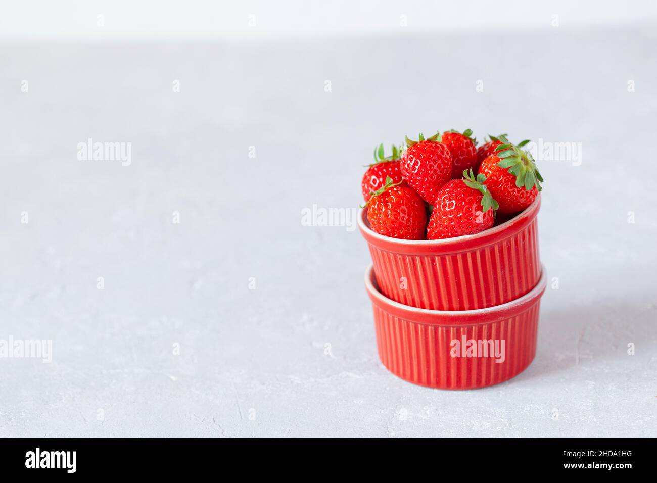 Rote Schalen voller frischer Erdbeeren, Seitenansicht, hellgrauer Hintergrund, selektiver Fokus, Kopierbereich Stockfoto