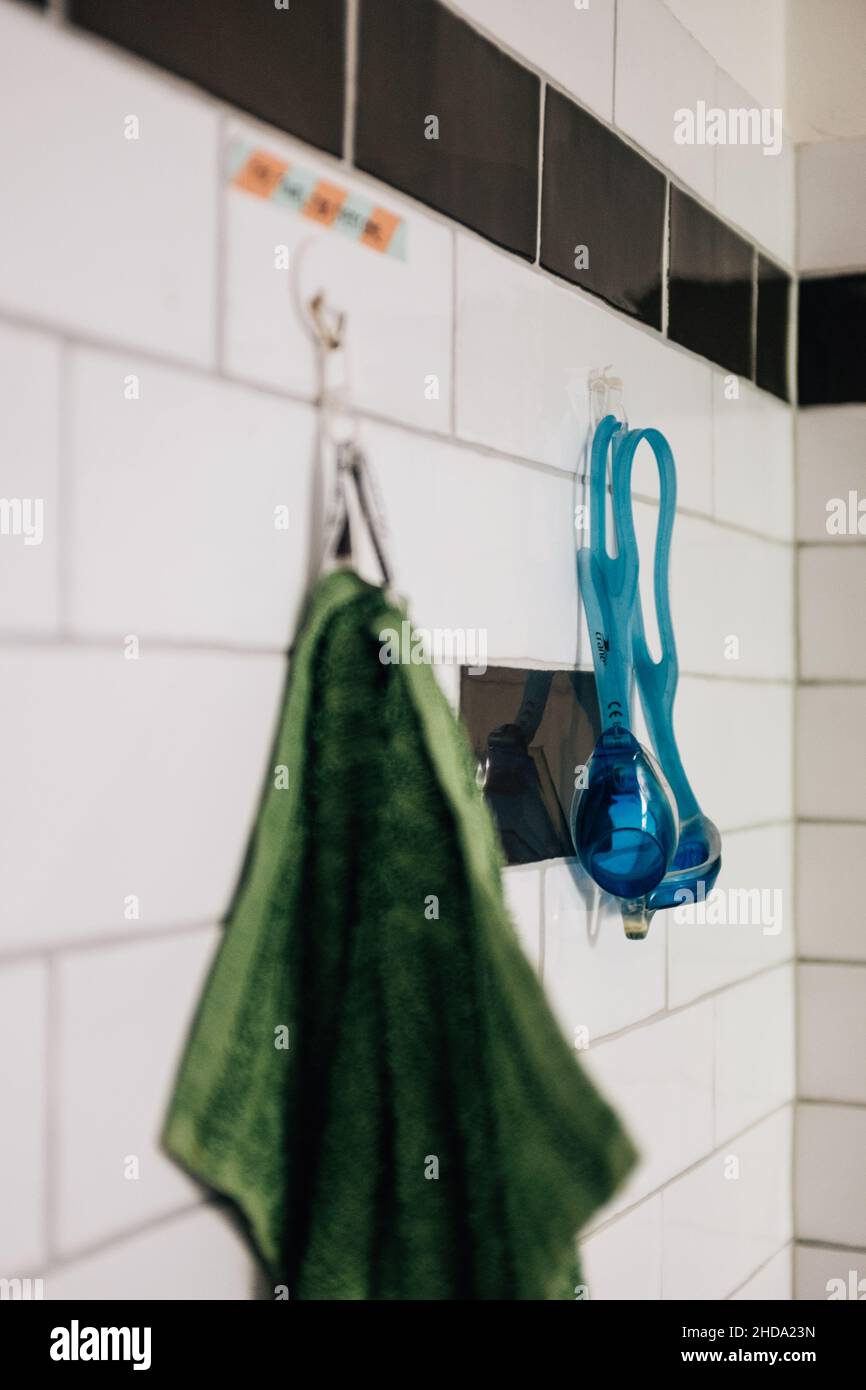 Nahaufnahme eines grünen Handtuchs an der Wand im Badezimmer mit blauen Schwimmgläsern Stockfoto