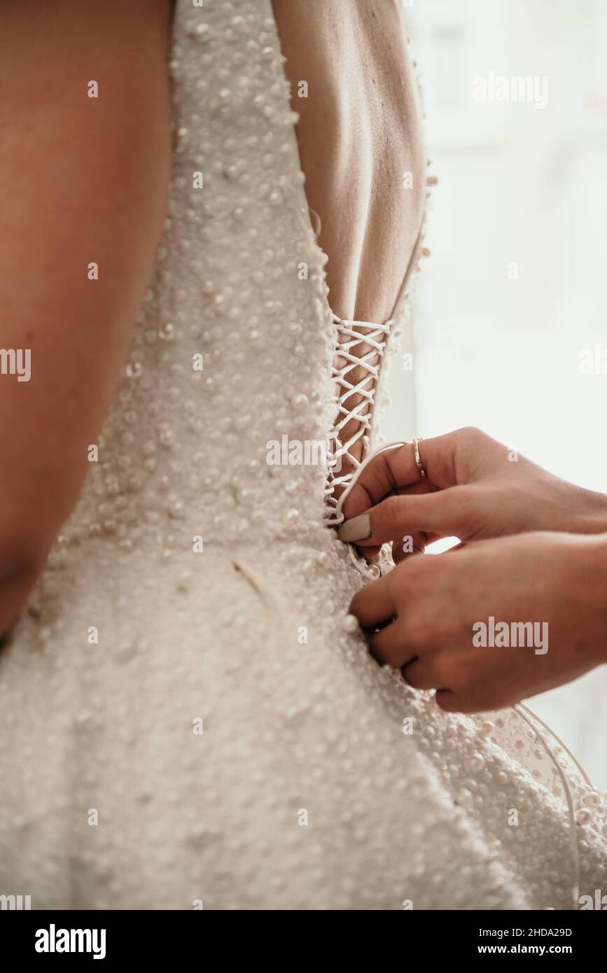 Vertikale Aufnahme der Hände, die ein Hochzeitskleid anschlagen Stockfoto