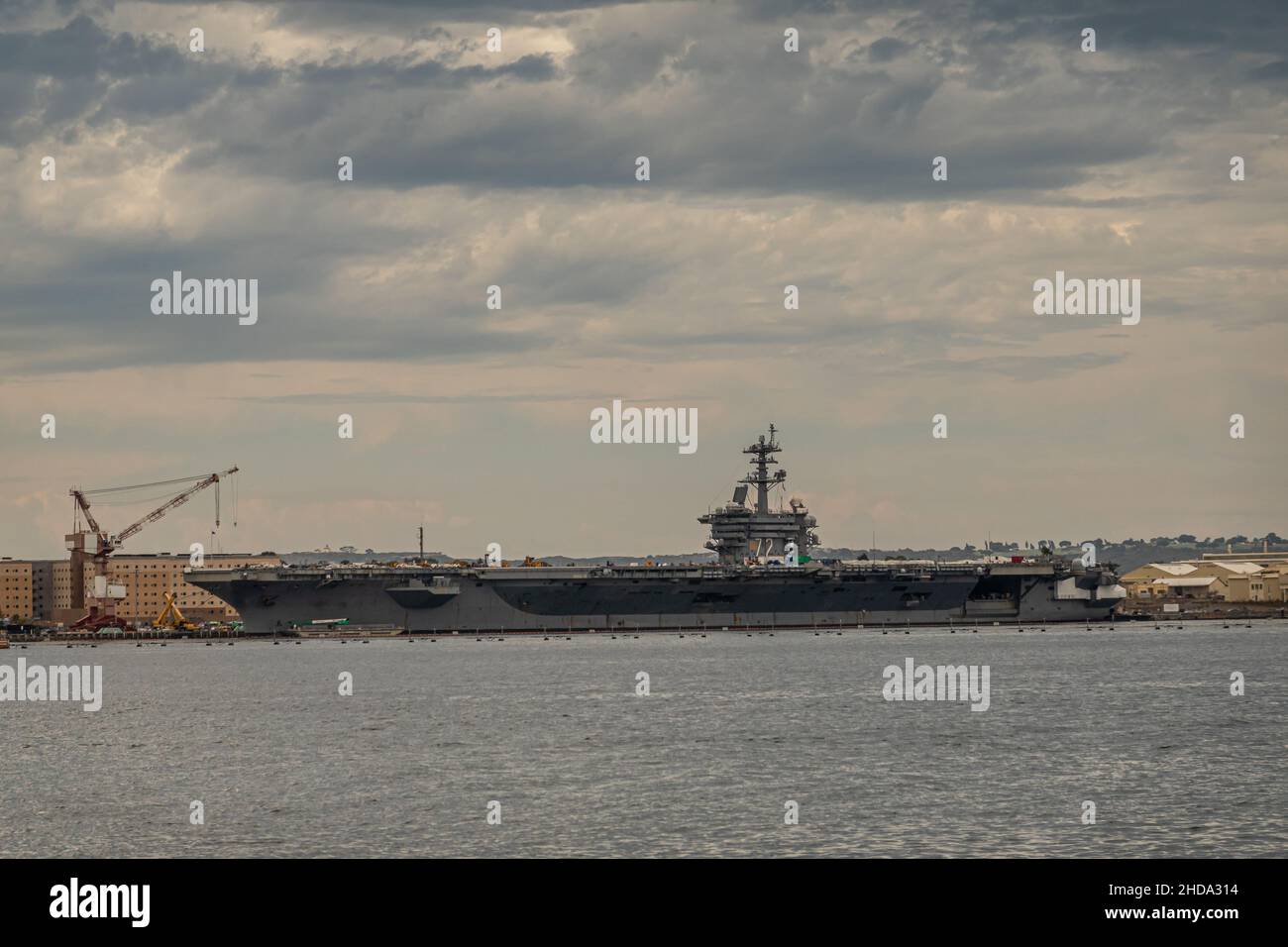 San Diego, Kalifornien, USA - 4. Oktober 2021: Der Flugzeugträger Abraham Lincoln dockte am Kai des Naval Supply Center unter der grauen Wolkenlandschaft hinter der grauen BA an Stockfoto