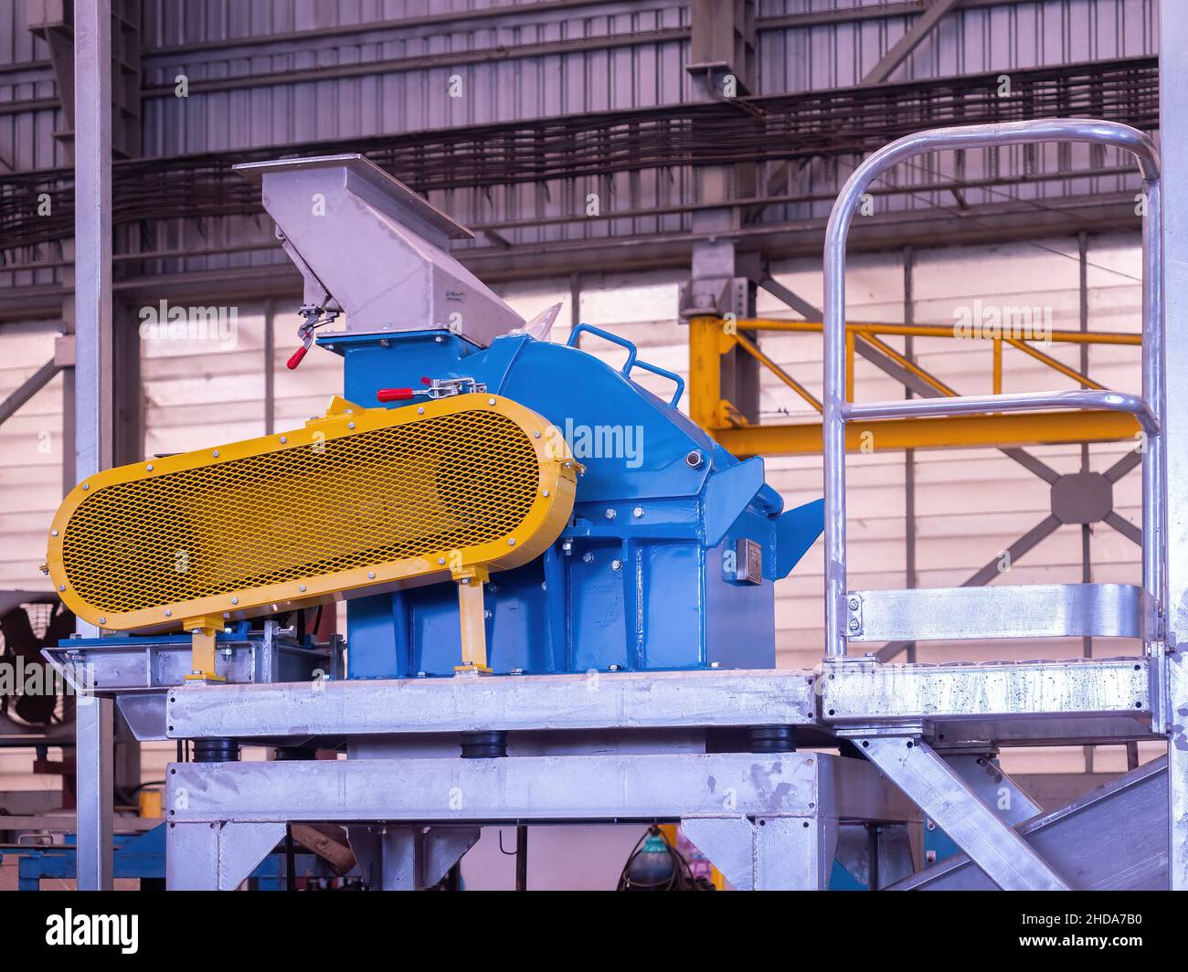Blaue und gelbe Hammermühle im industriellen Umfeld Stockfoto