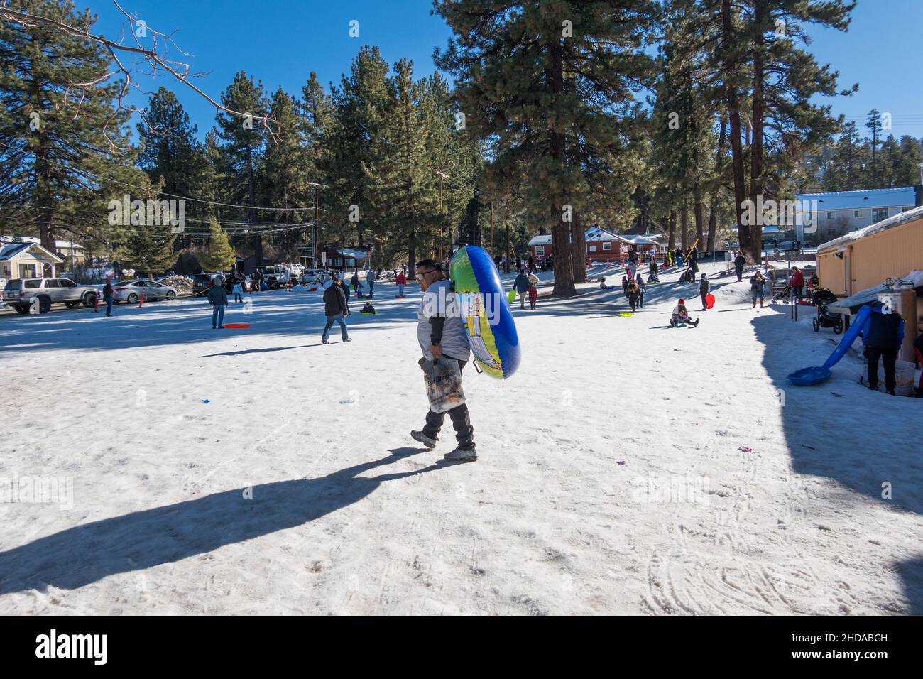 Ein Mann, der im öffentlichen Park in Big Bear Lake, Kalifornien, USA, auf dem Schnee mit aufgeblähtem Schneeröhr zur Piste läuft Stockfoto
