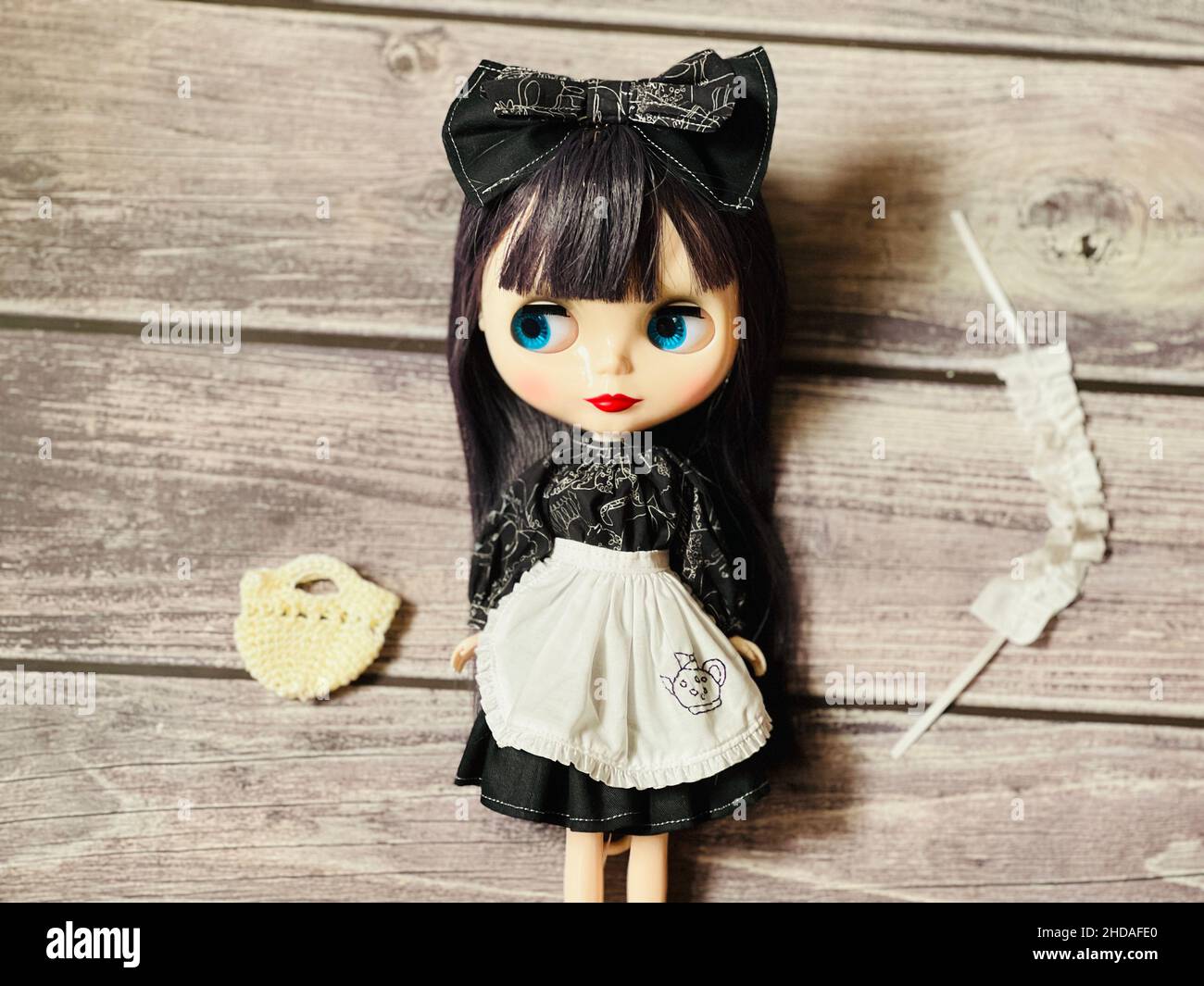 Niedliche Mädchen Puppe in einem Dienstmädchen Kostüm auf einem Holztisch Stockfoto