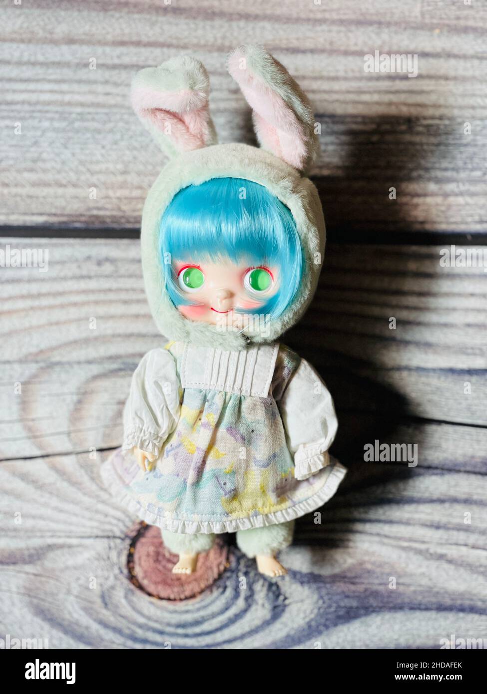 Vertikale Aufnahme einer niedlichen Puppe mit einem Hasen-Kostüm auf einem Holztisch Stockfoto